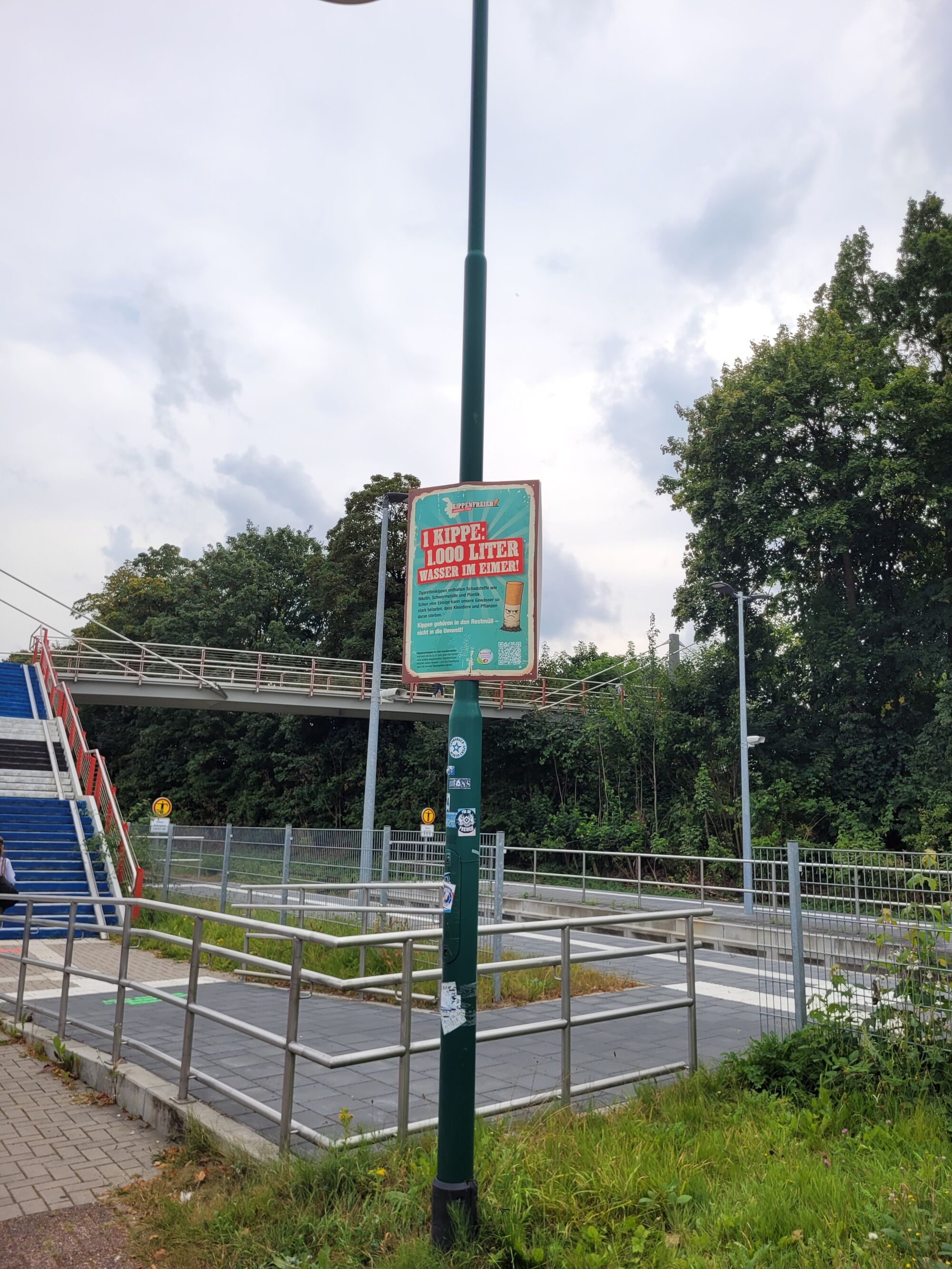  – Ein Plakat an einem Laternenmast. Es trägt in roter Schrift die Aufschrift 