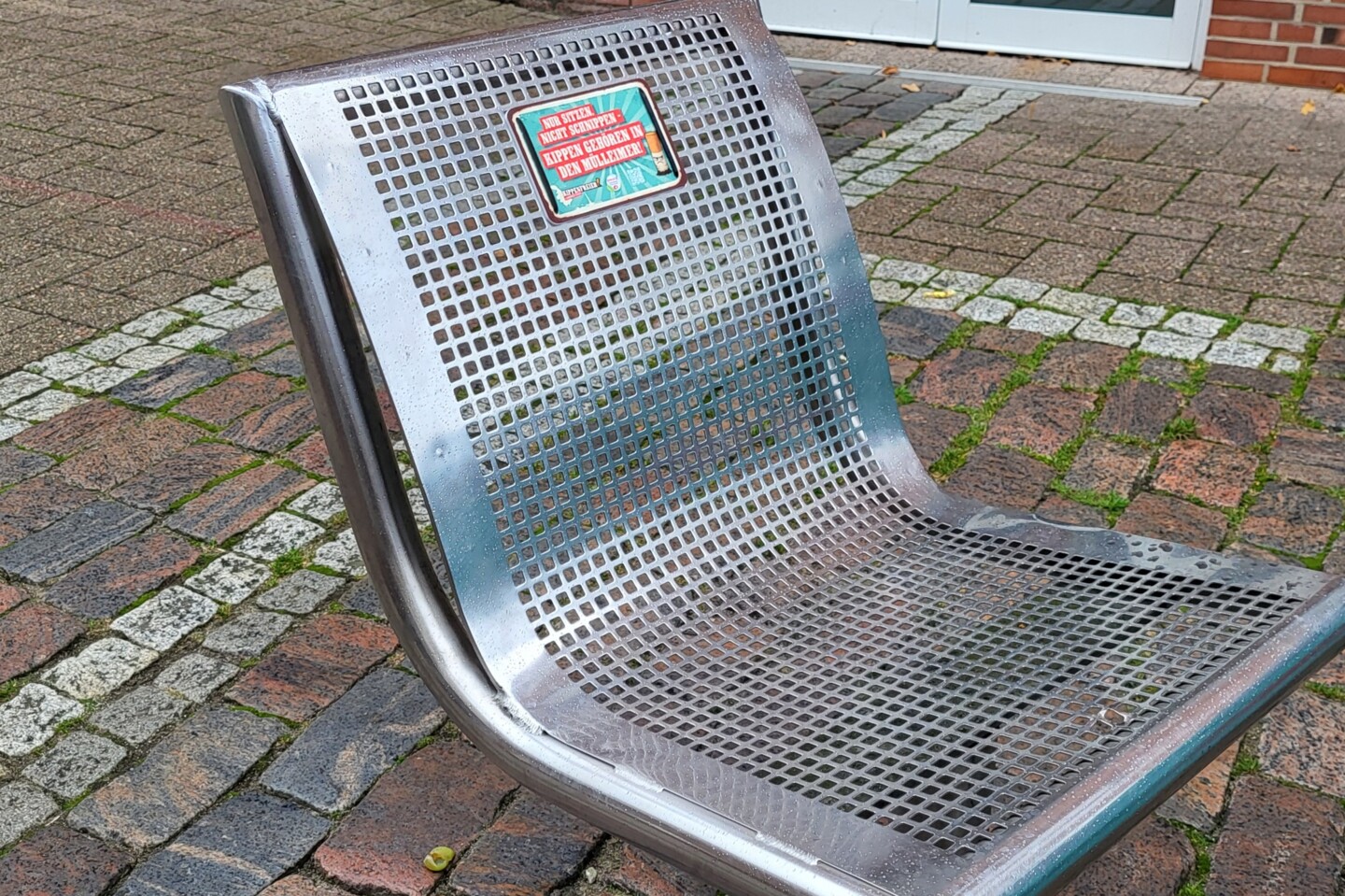 Ein Metallstuhl in einer Fussgängerzone mit dem A 6 Parkbankschild auf dem steht 