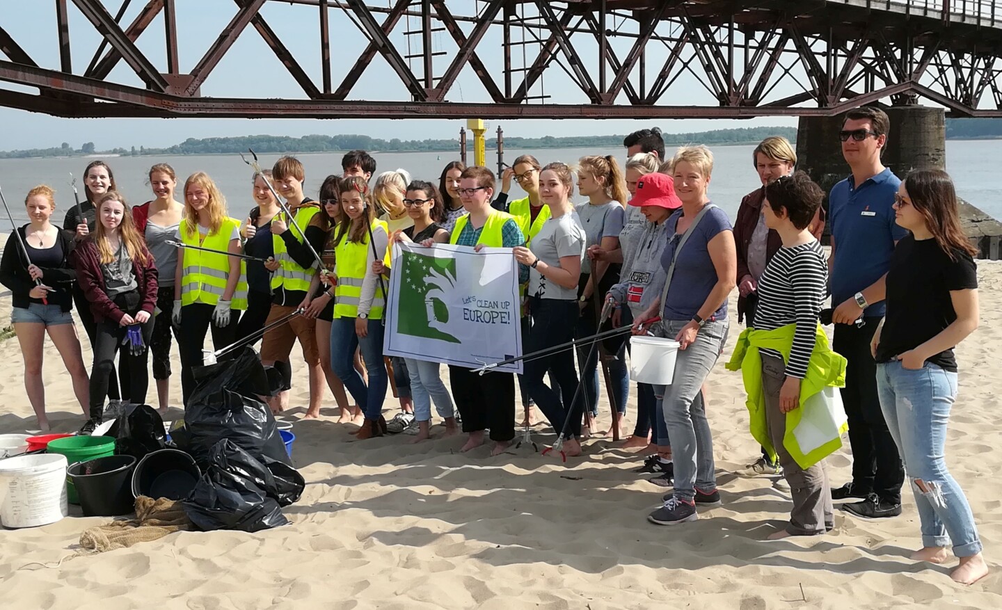 Schülergruppe mit Abfallberaterinnen am Abbenflether Strand mit Müllsäcken und Let’s Clean Up Europe Banner