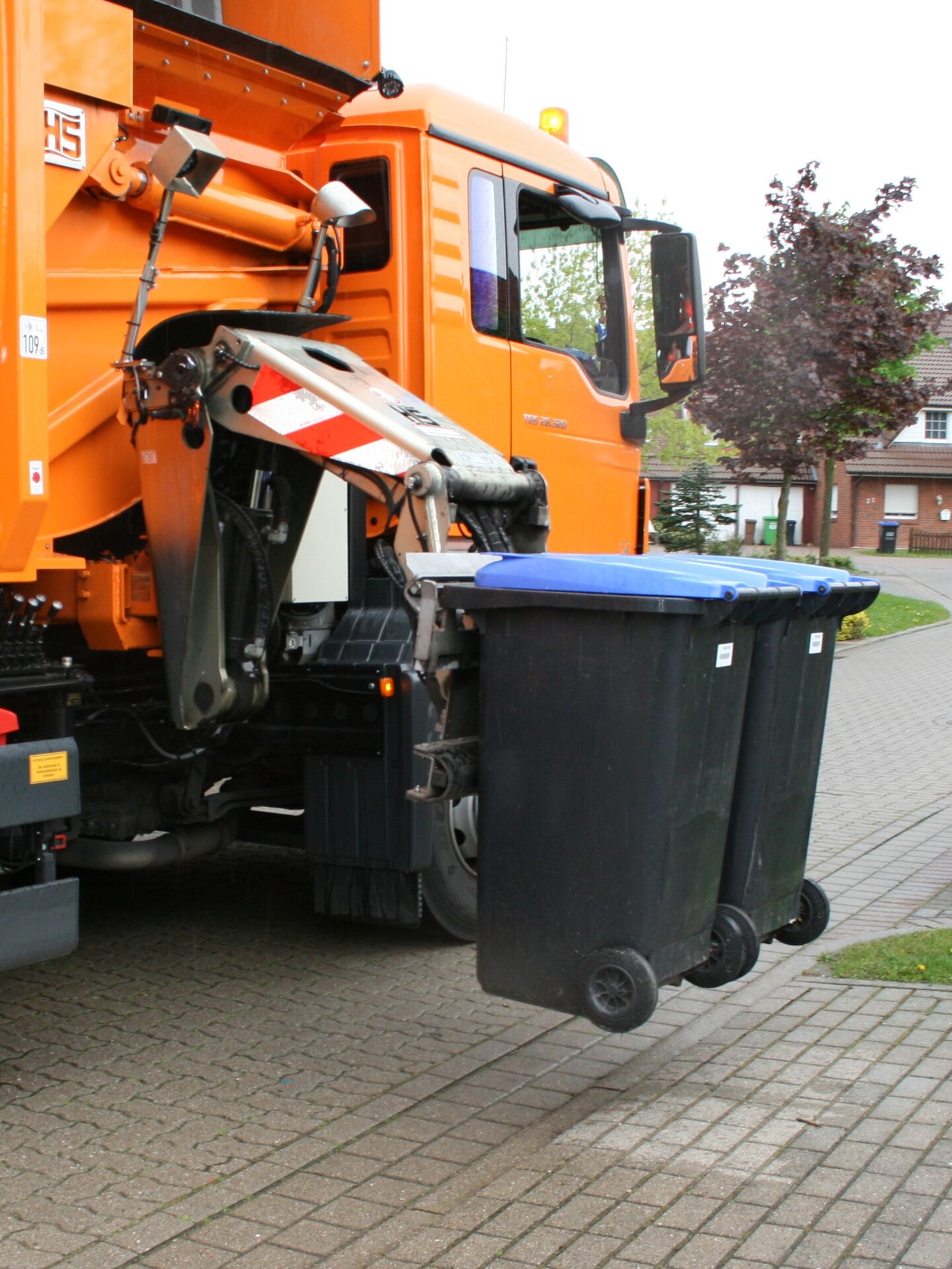 Müllfahrzeug entleert zwei Altpapiertonnen mit Seitenladertechnik