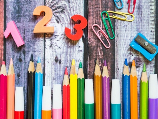 Bunte Stifte und Büroklammern auf Holzdielen